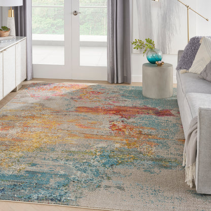 Abstract multicolor area rug with teal, orange, blue and beige tones in a modern living room with gray sofa.