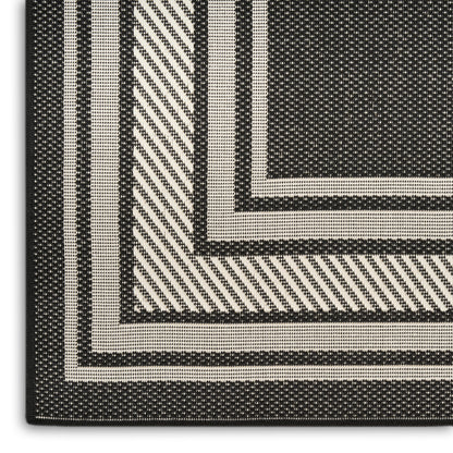 Close-up of a black & cream woven rug with nested rectangular borders and diagonal stripe texture.