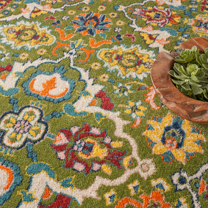 Colorful oriental rug with green base and vibrant floral motifs; wooden bowl with succulents resting on the side.