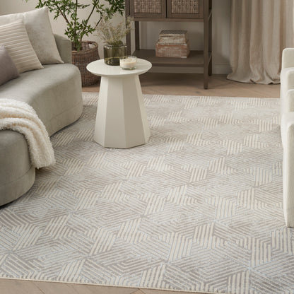 Soft neutral living room with beige sofa, cream geometric rug, white angular pedestal table, and woven baskets.