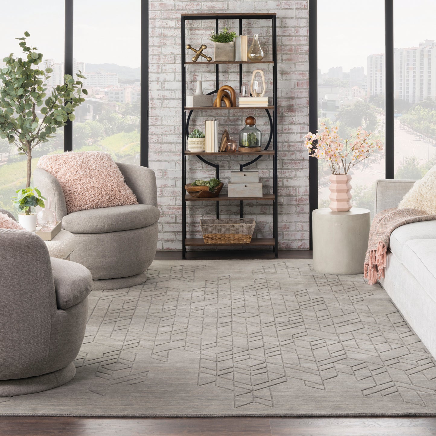 Modern industrial living room with a black metal-framed bookshelf, gray seating, brick wall, and geometric rug.