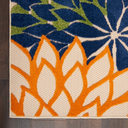 Corner of a textured flat-weave rug with bold orange leaf motifs on a white field, plus blue floral and green accents.