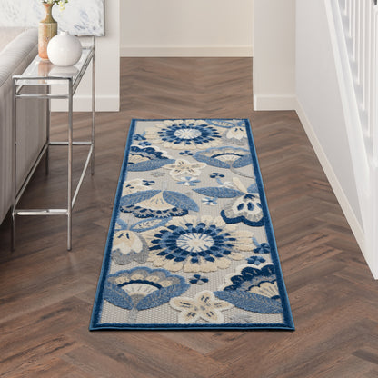 Blue & white floral woven runner rug with dark blue border on a herringbone wood hallway floor.
