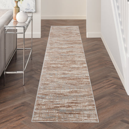 Long beige-taupe abstract runner rug in a modern hallway with dark herringbone wood floor.