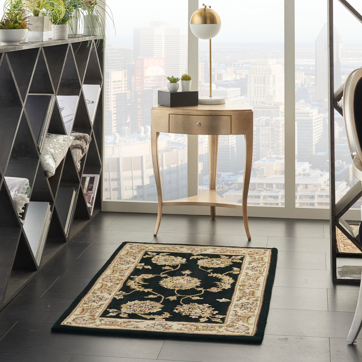 Curved wooden console with drawer and gold lamp; potted plants, triangular shelf, black-and-cream Persian rug, city view.