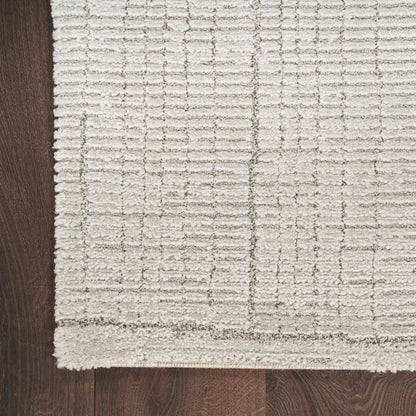 Cream textured area rug with a raised grid pattern on dark wood floor, thick edge border visible.