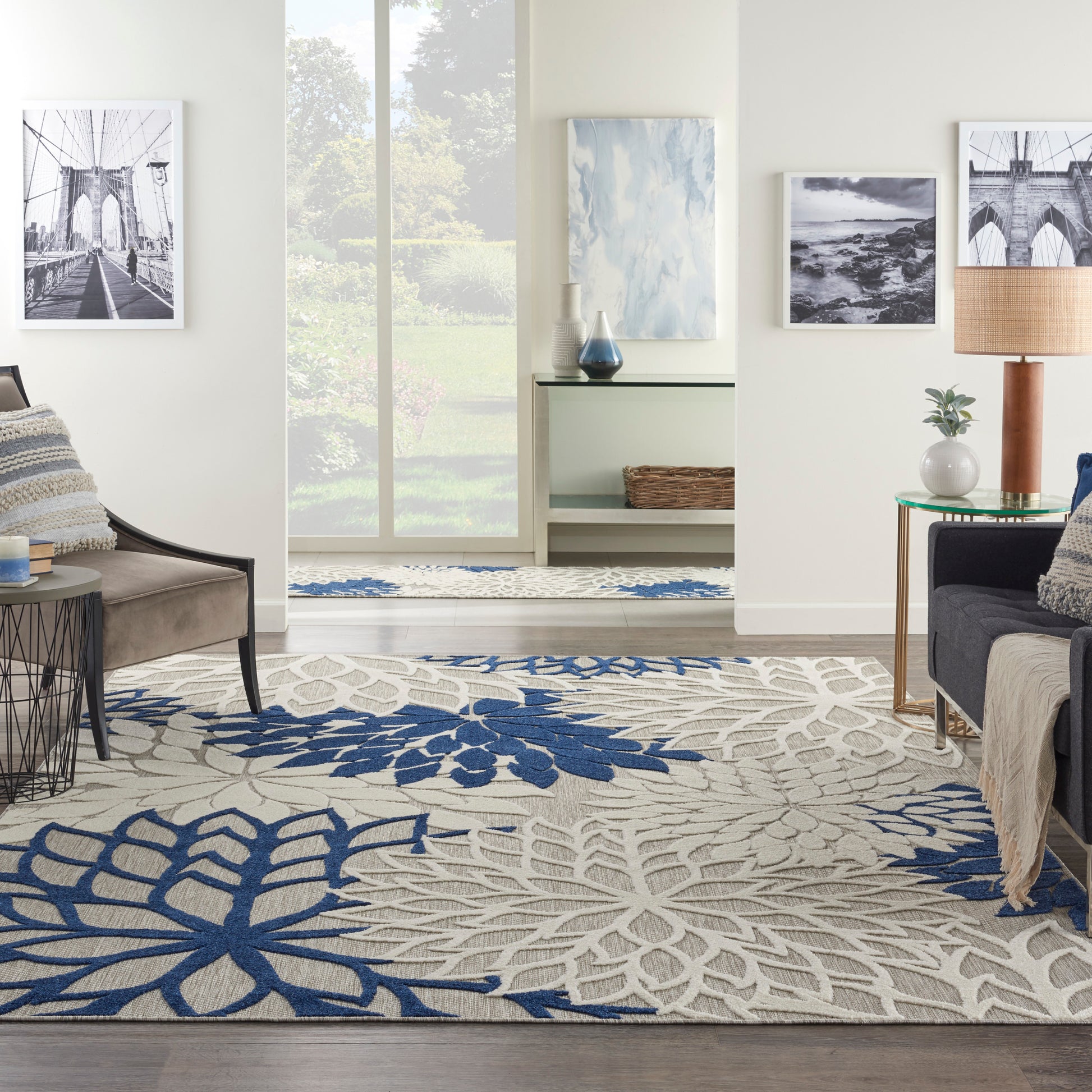 Living room with beige and blue floral area rug, neutral sofa and chair, wall art, and large window.