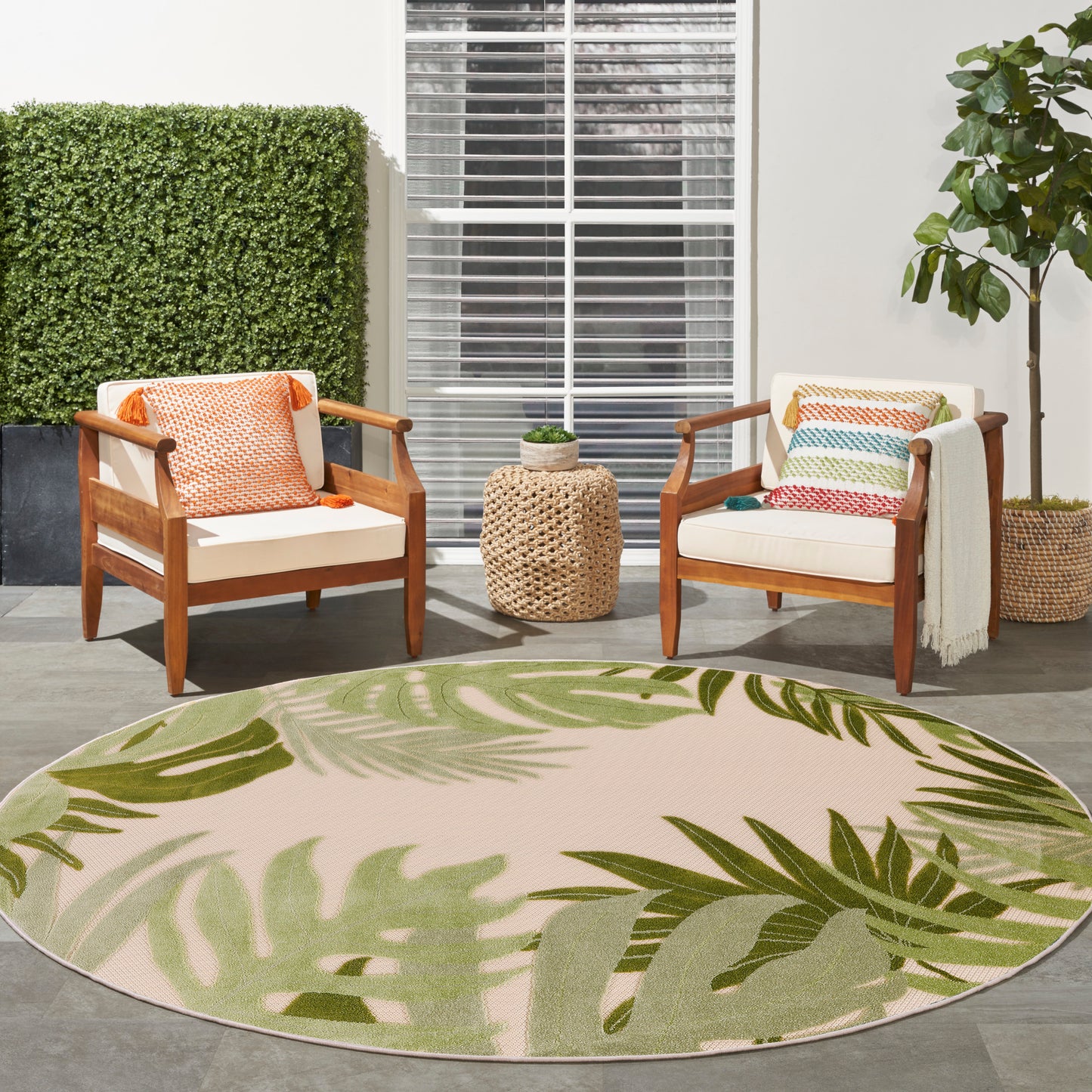 Outdoor round rug, 8 ft diameter, with a large leaf pattern on a patio.