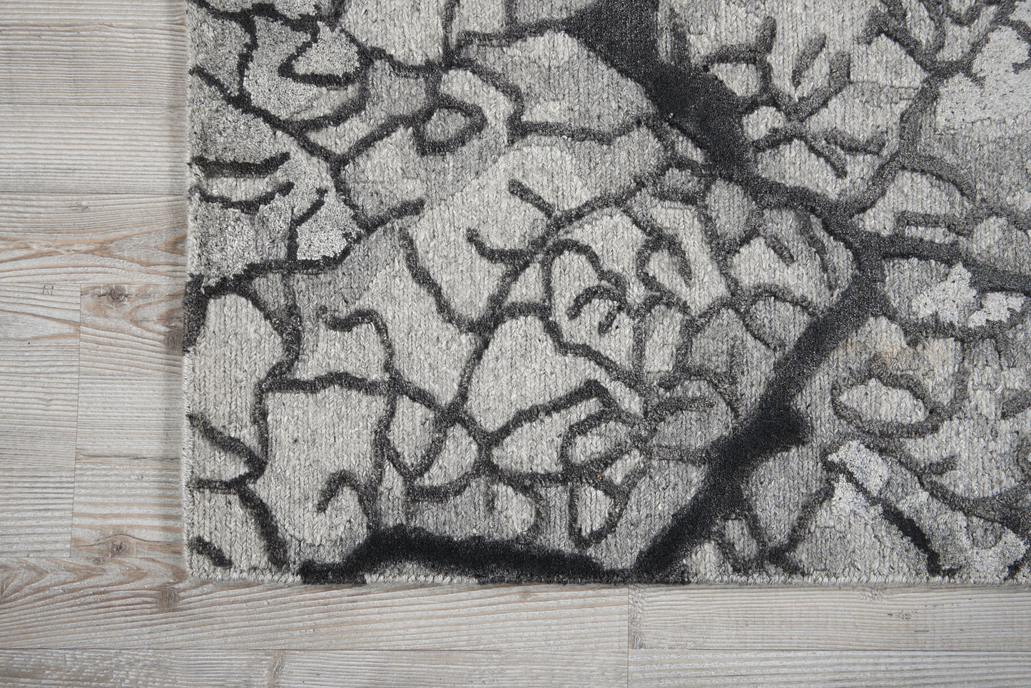 Gray shag rug with black crackle pattern on light wood floor.