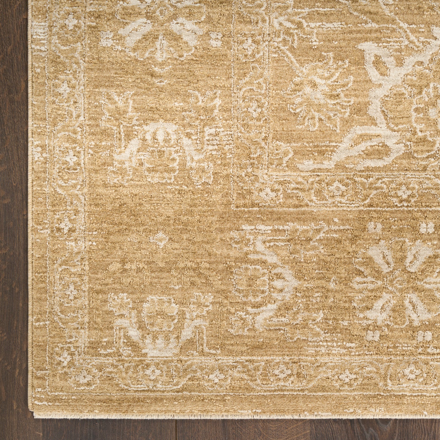 Beige oriental area rug with ivory floral border on dark wood floor.