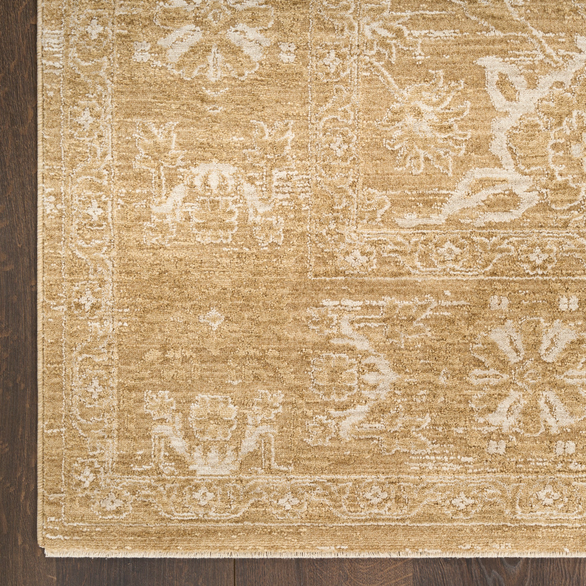 Beige oriental area rug with ivory floral border on dark wood floor.