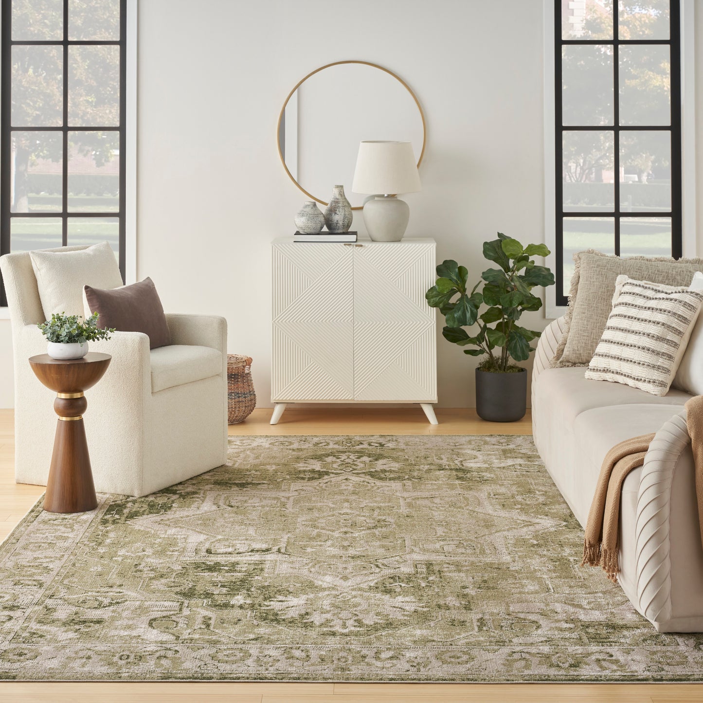 Cream sofa and armchair, olive-green patterned vintage rug (7' x 9'), geometric cream cabinet with round mirror, lamp and plant.