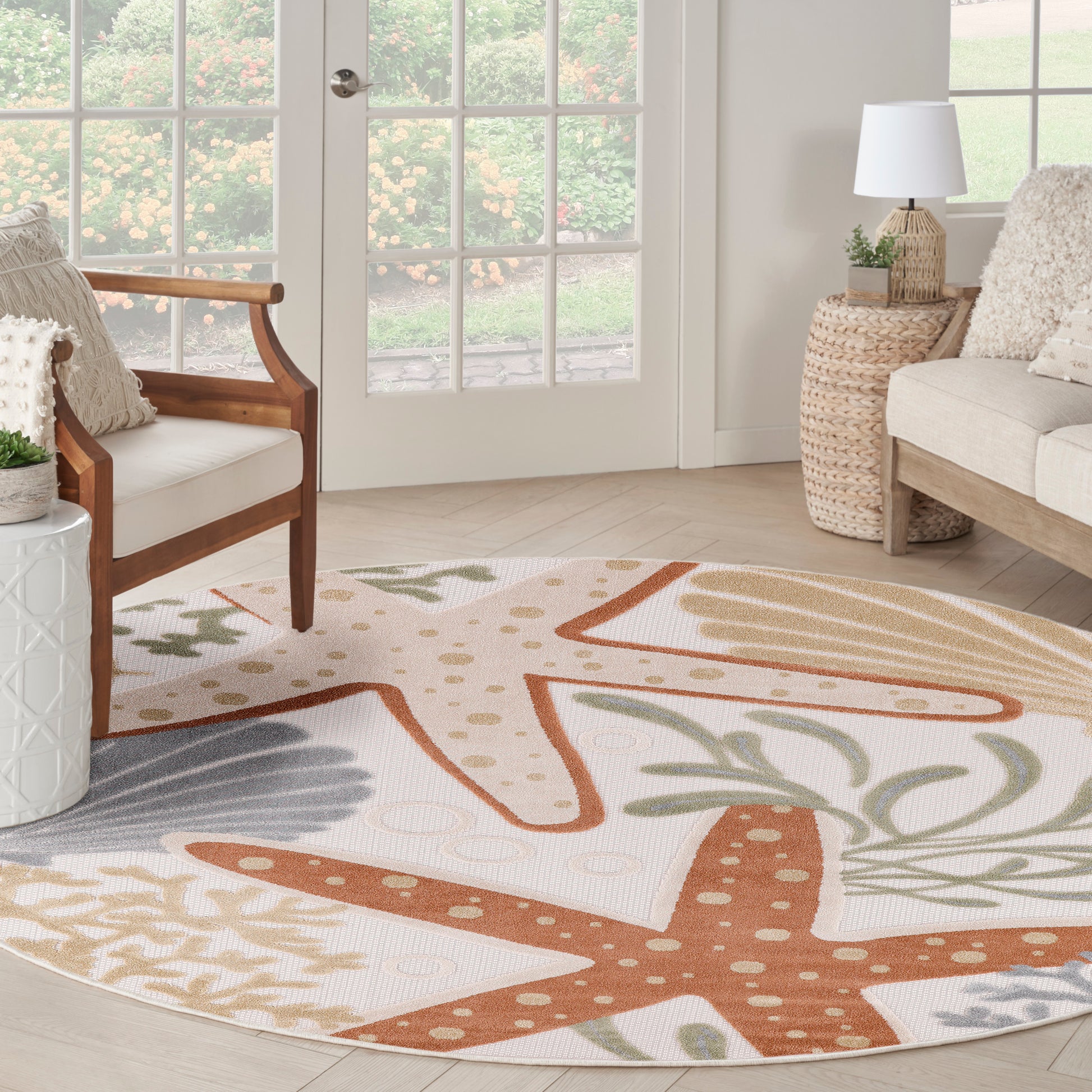Round outdoor rug with orange starfish and palm leaf patterns on a cream background.