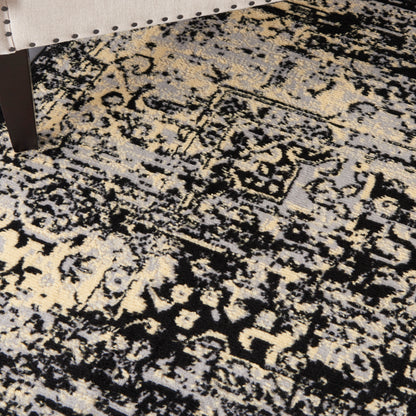Distressed oriental area rug with black, ivory, gray & tan tones under furniture leg.