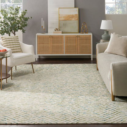 Cream sofa and armchair in a cozy living room with a woven rattan cabinet, abstract art, plant, and blue zigzag rug.