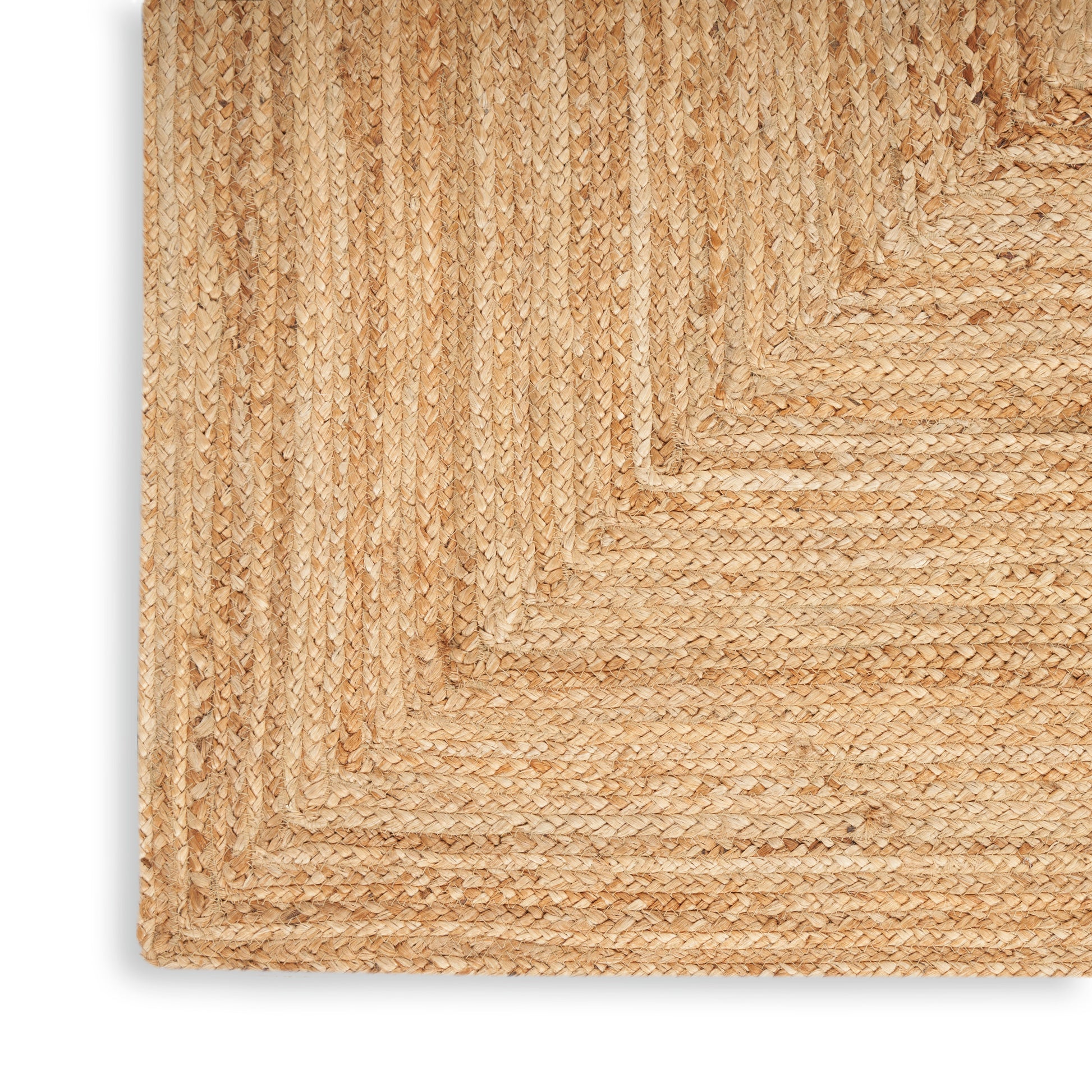 Natural jute braided rug corner in beige/tan; textured coastal rustic weave.