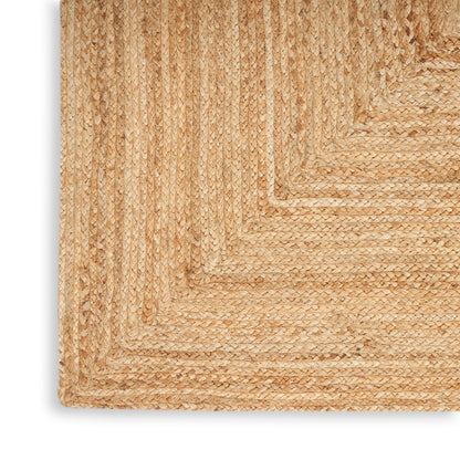 Natural jute braided rug corner in beige/tan; textured coastal rustic weave.