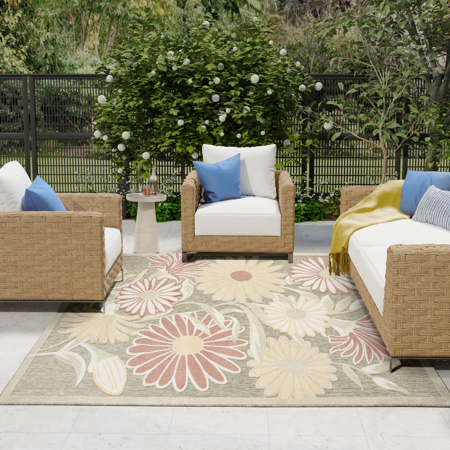 Outdoor rug, 8' x 11', with a large floral pattern on a patio amid lush greenery.