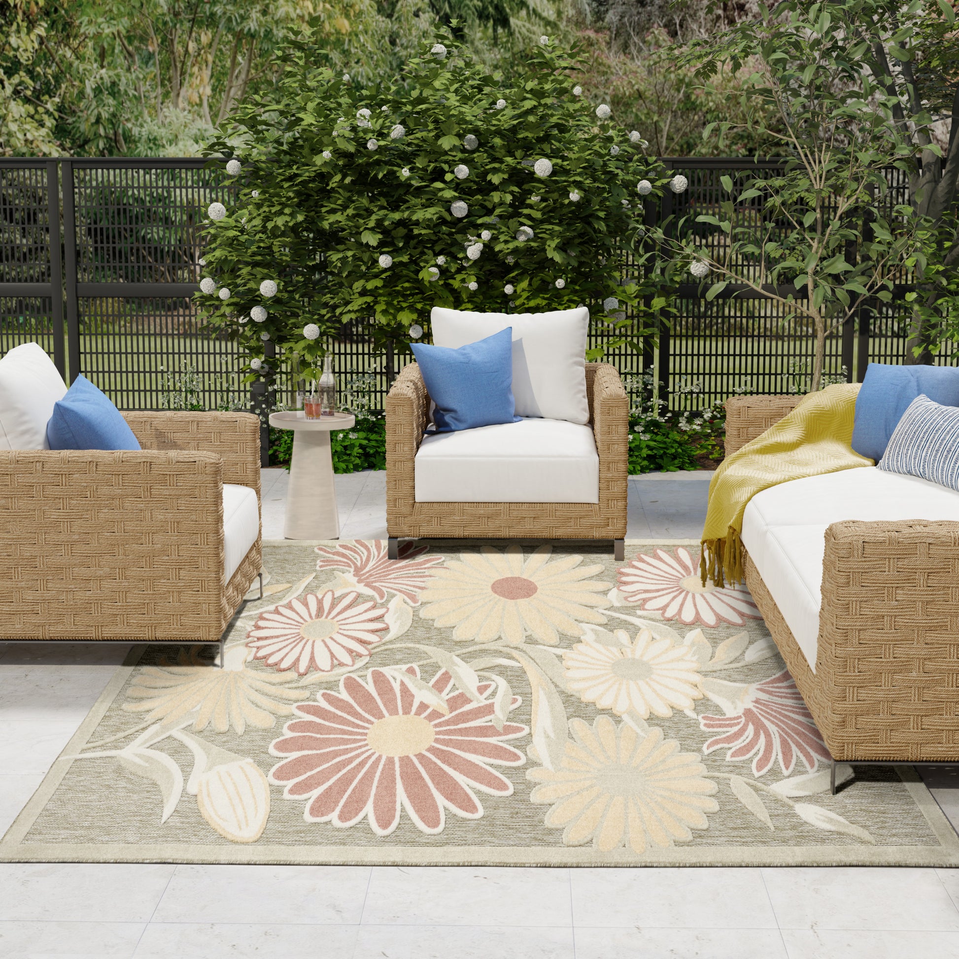 Outdoor rug, 8' x 11', with a large floral pattern on a patio amid lush greenery.
