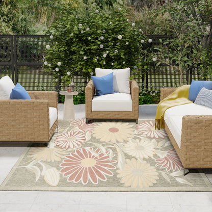 Outdoor rug, 8' x 11', with a large floral pattern on a patio amid lush greenery.