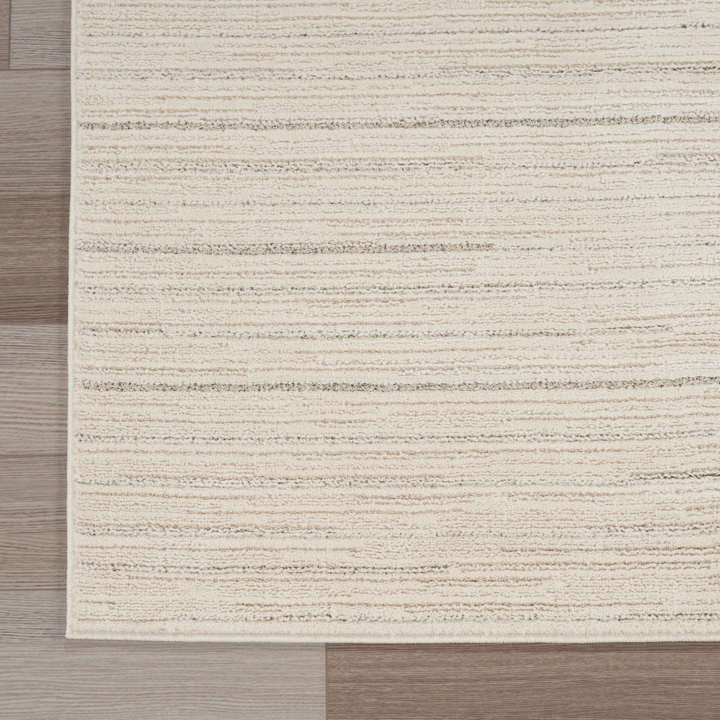 Beige textured rectangular rug with subtle horizontal stripes on light wood floor.