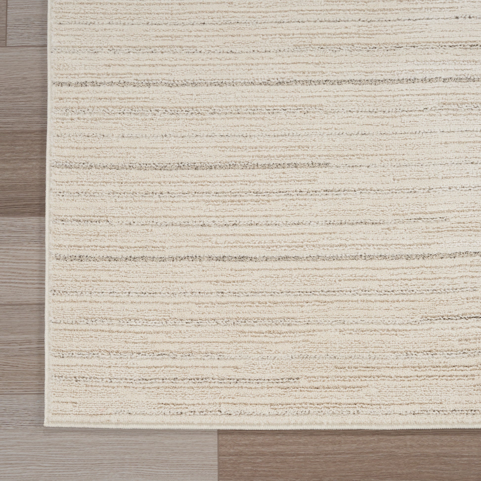 Beige textured rectangular rug with subtle horizontal stripes on light wood floor.