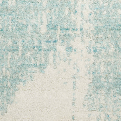 Light blue and cream abstract rug with a distressed pattern and plush pile.