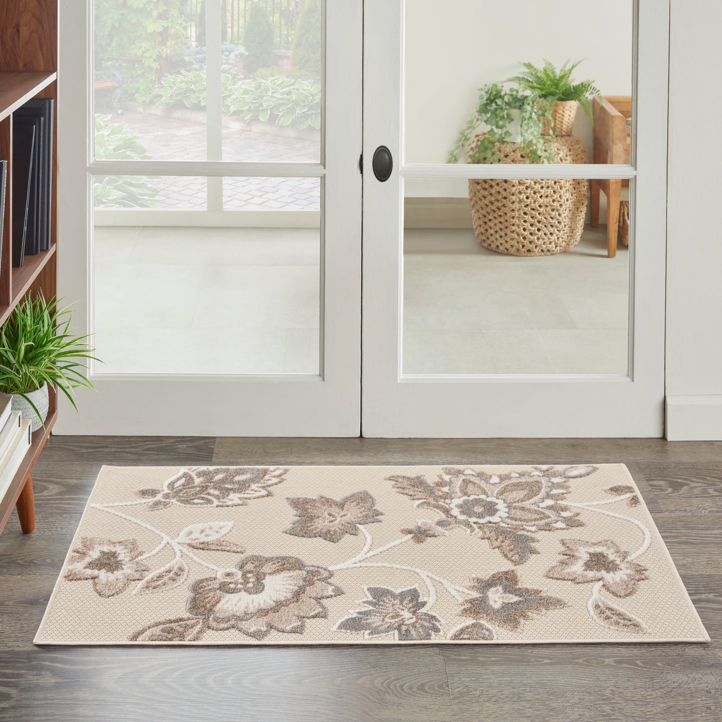 Beige floral area rug with taupe-brown flowers, rectangular, placed in an entryway on dark wood floor