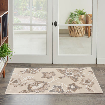 Beige floral area rug with taupe-brown flowers, rectangular, placed in an entryway on dark wood floor