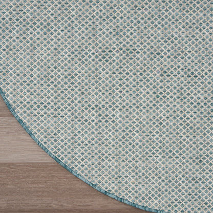 Round woven rug with teal and ivory diamond lattice pattern, teal edge, on light wood floor.