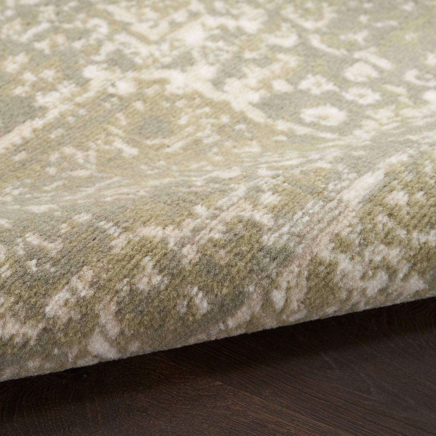 Soft beige and ivory damask-pattern runner rug with thick pile, edge folded on dark wood floor.