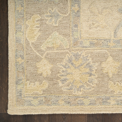 Beige & pale blue floral patterned area rug with ornate medallions & border on dark wooden floor.