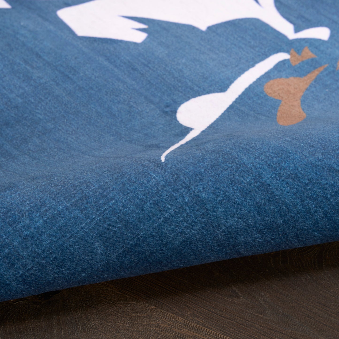 Blue fabric with white abstract shapes and a small brown accent, close-up of printed throw blanket texture.
