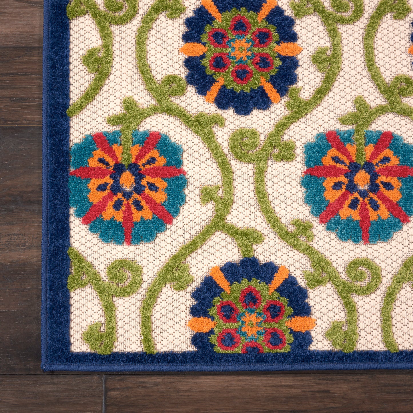 Decorative woven rug with green vines and colorful circular floral medallions on a white lattice, bordered in dark blue.