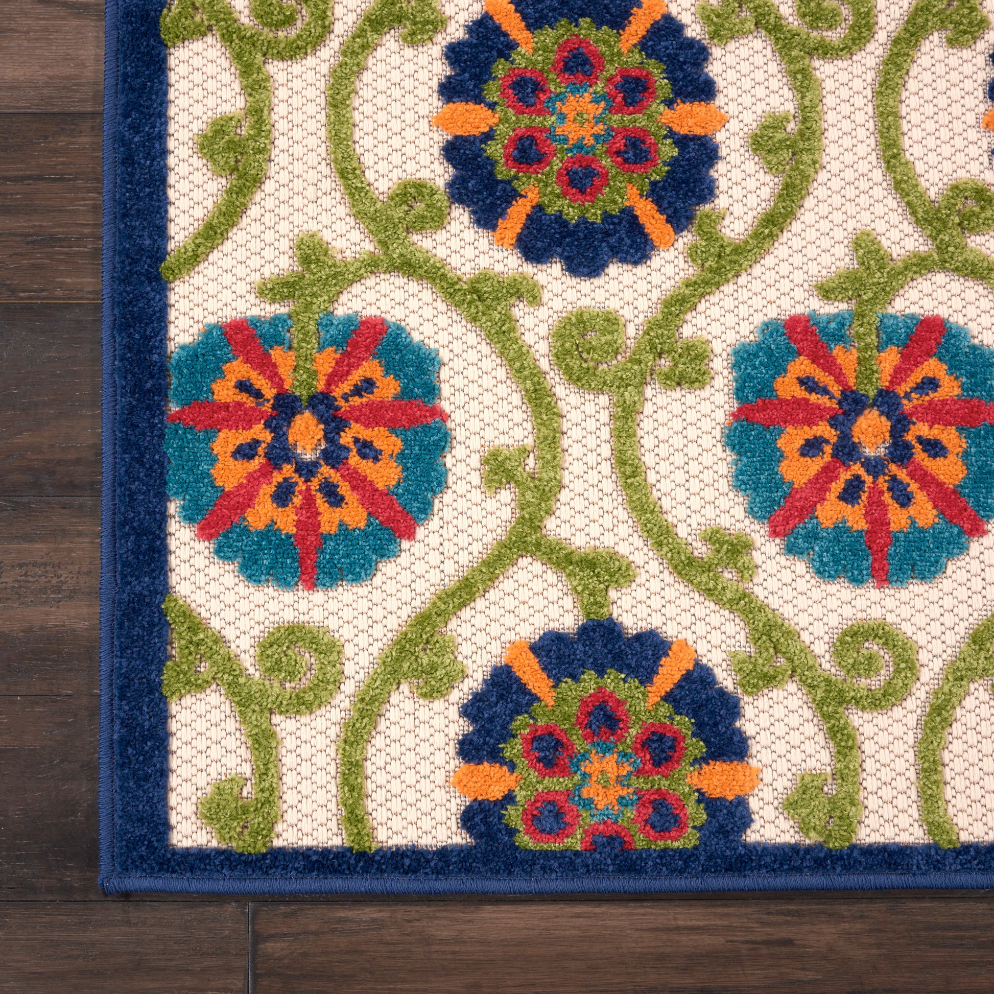 Decorative woven rug with green vines and colorful circular floral medallions on a white lattice, bordered in dark blue.