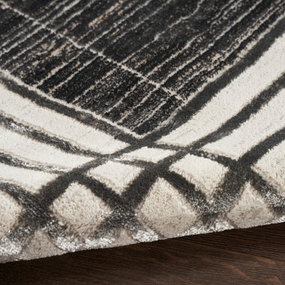Cream and charcoal geometric shag rug with diamond line patterns atop dark wood flooring.