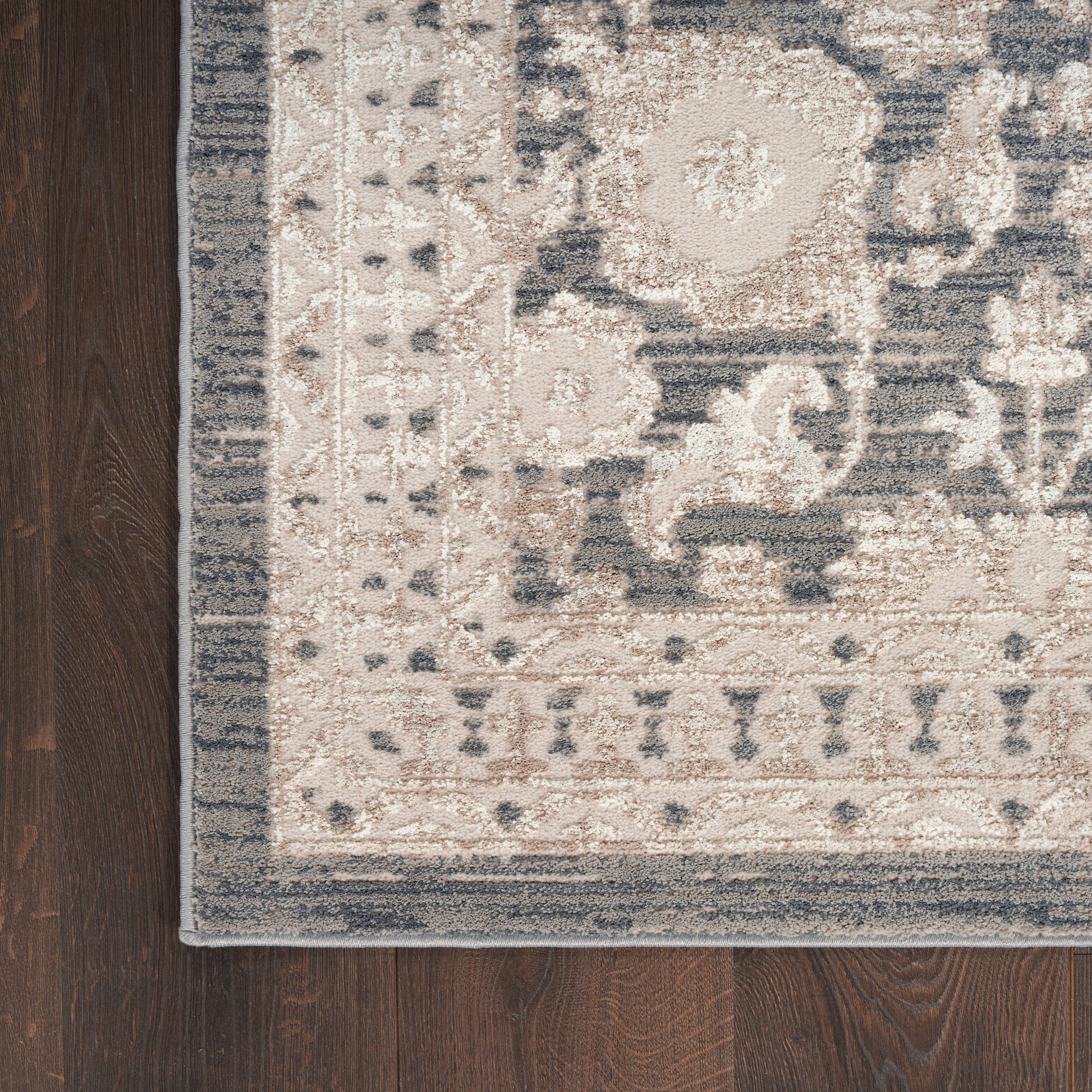 Traditional beige and gray Persian-style rug on dark wood floor with an intricate damask border.
