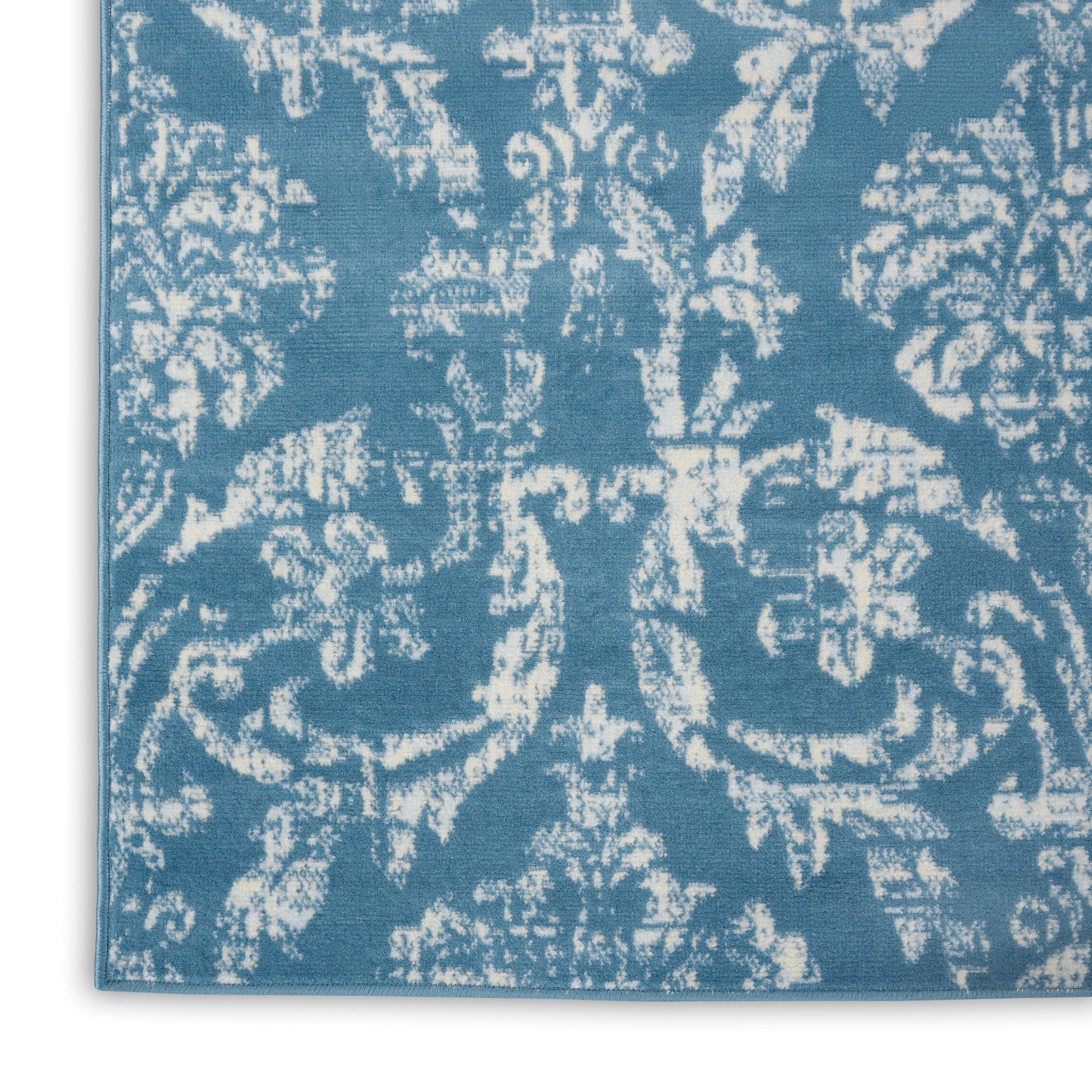 Blue damask-patterned rug with white ornate scroll motifs; woven rectangular decorative floor rug.