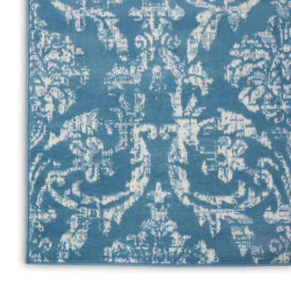 Blue damask-patterned rug with white ornate scroll motifs; woven rectangular decorative floor rug.