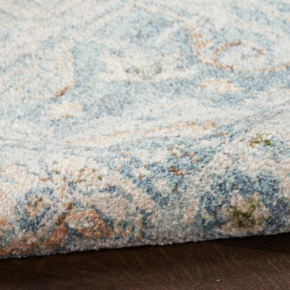 Soft blue & cream patterned tufted rug with subtle floral motifs on a dark wood floor.