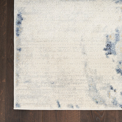 Rectangular cream rug with soft blue abstract accents on dark hardwood floor.