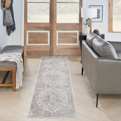 Light blue-gray Persian-style runner rug in a bright living room between a gray sofa and a wooden bench.