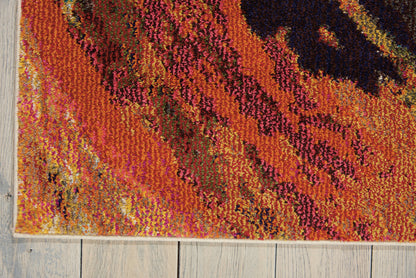 Vibrant abstract area rug in orange, pink and purple with black accents; woven textile on light wood floor.