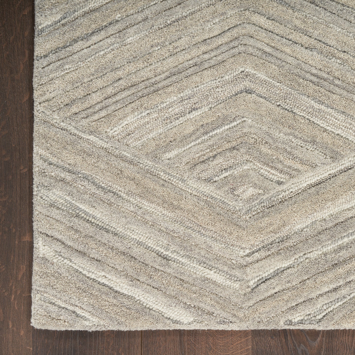 Beige shag rug with raised geometric diamond/chevron pattern on dark wood floor.