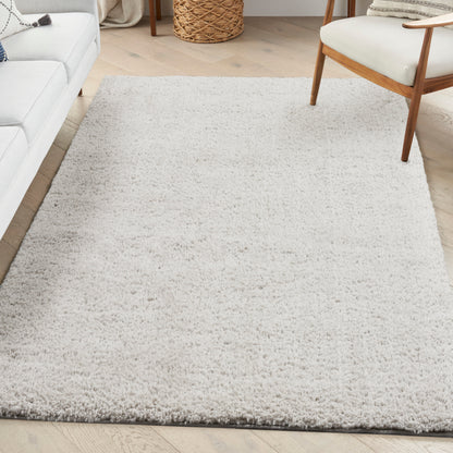 Ivory shag rug on light wood floor in bright living room; cream sofa and mid-century chair.