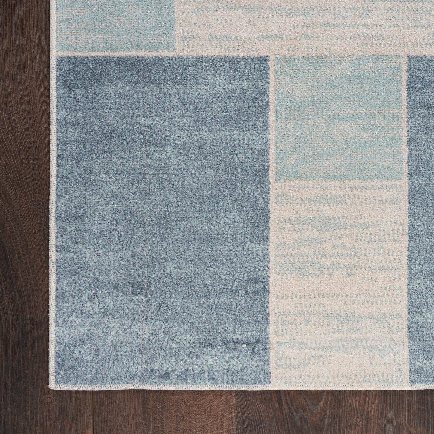 Geometric blue area rug with navy, light blue and cream blocks on a dark wood floor