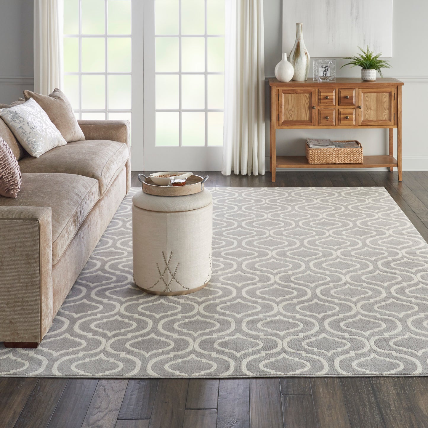 Gray area rug with a white geometric wave pattern in a cozy living room beside a beige sofa and wooden console.