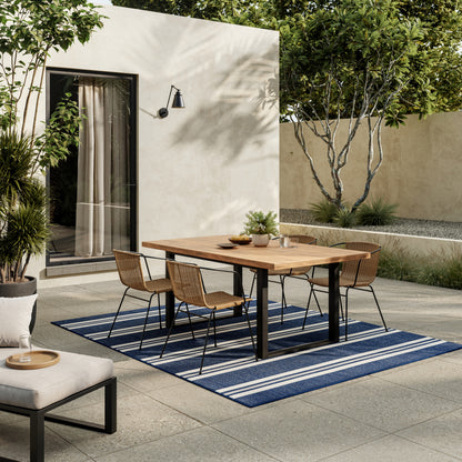 Blue striped outdoor rug, 4' x 6', laid on a beige stucco courtyard.