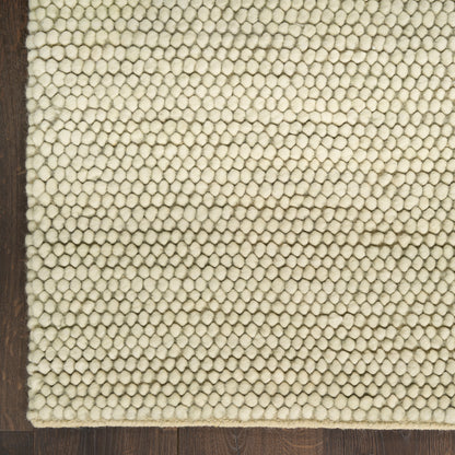 Cream looped-pile rug with tight natural-fiber loops on dark hardwood floor.