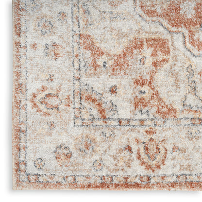 Close-up of a distressed beige area rug with rust red and blue oriental floral motifs and a decorative border.